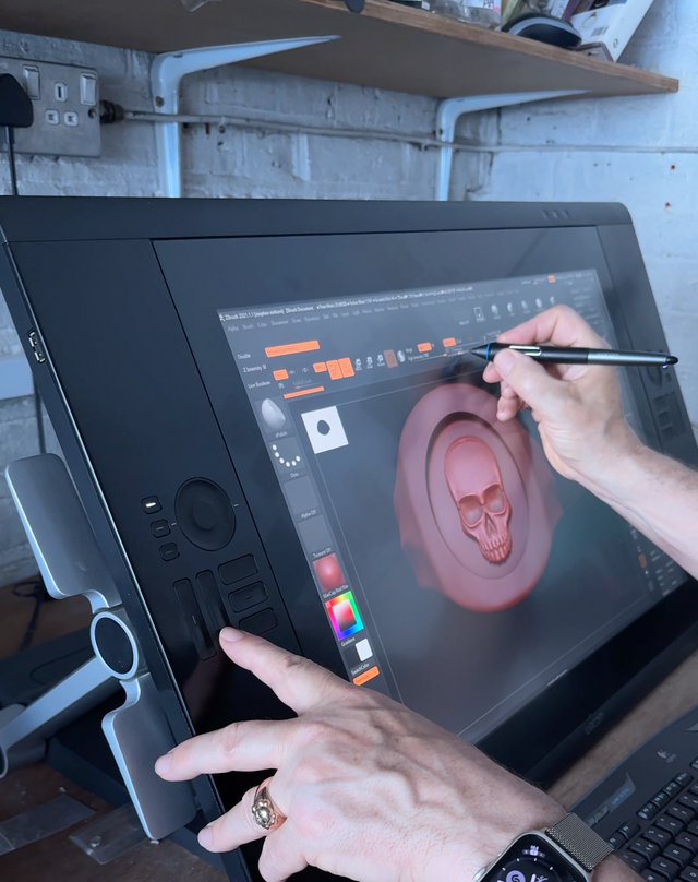 A man is drawing a signet skull ring on a computer program.
